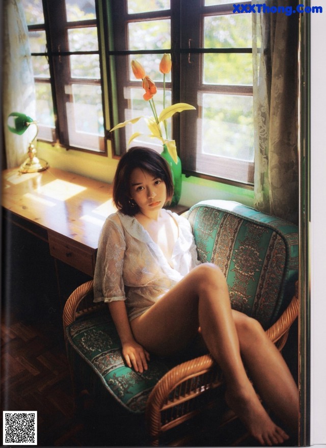 A woman sitting on a chair in front of a window.