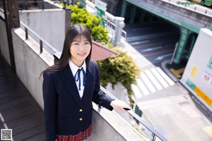 A woman in a school uniform standing in front of a door.