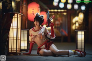 A woman in a red and white outfit sitting on the floor.