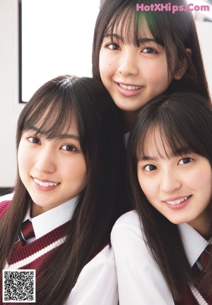 A group of three young women sitting on top of a bed.