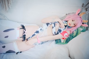 A woman with pink hair is laying on a bed.