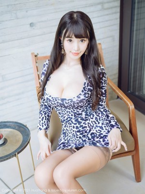 A woman sitting on a couch in a leopard print dress.