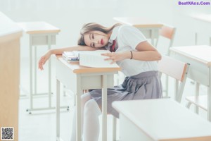 A naked woman sitting on the floor in a classroom.