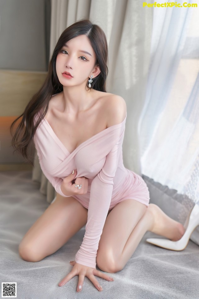 a woman in a pink dress sitting on a bed