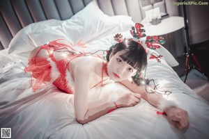 A woman in a red dress sitting on a couch.