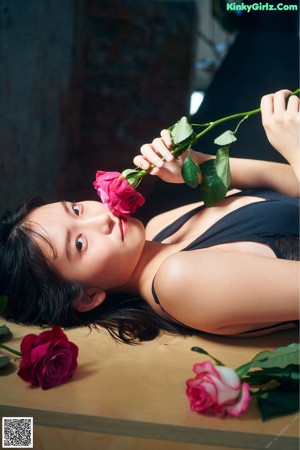 A woman sitting on the steps of a building holding a bouquet of flowers.