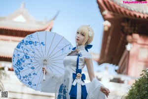 A woman in a white dress holding an umbrella.