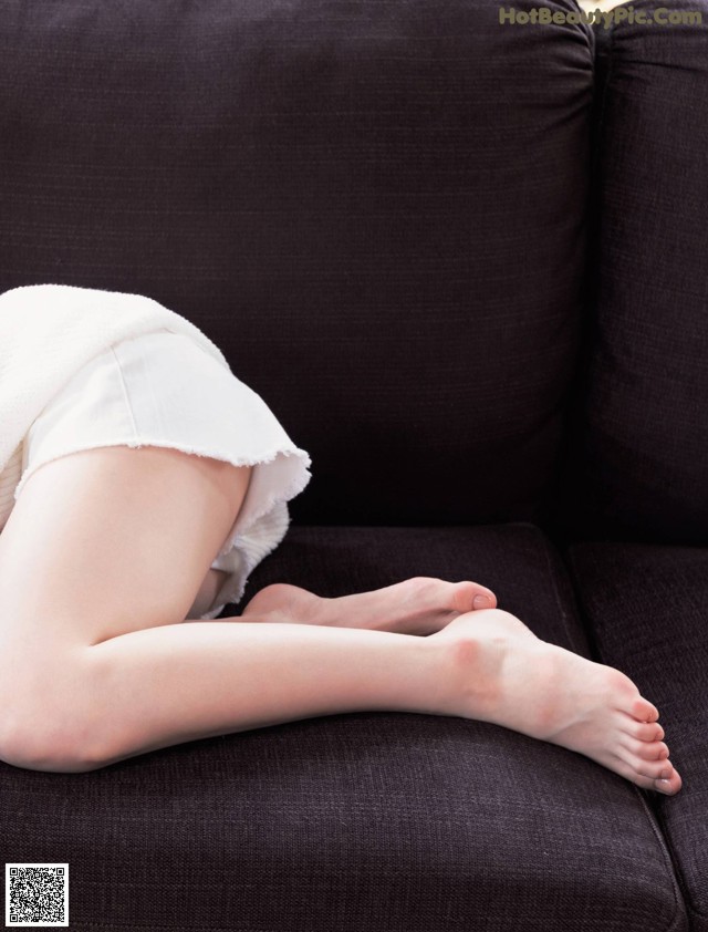 A woman laying on a couch with her legs crossed.