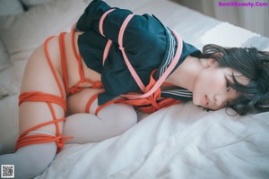 A woman in a sailor outfit sitting on a bed.