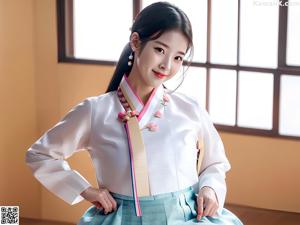 A woman in a pink and white hanbok sitting on the floor.