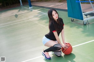 A woman holding a basketball on a basketball court.