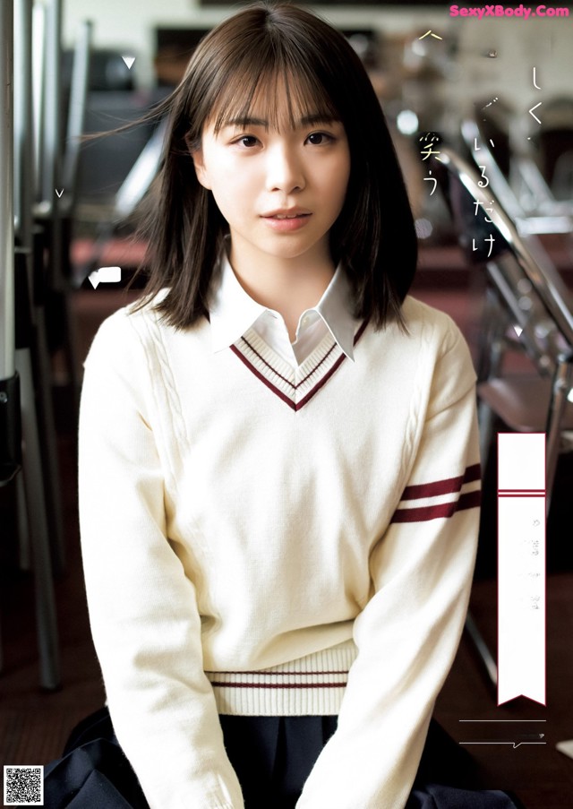 A young woman in a white sweater sitting on a chair.