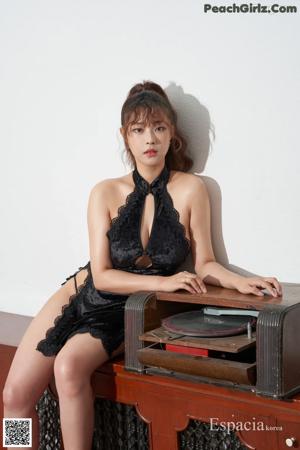 A woman in a black dress sitting on a brown chair.