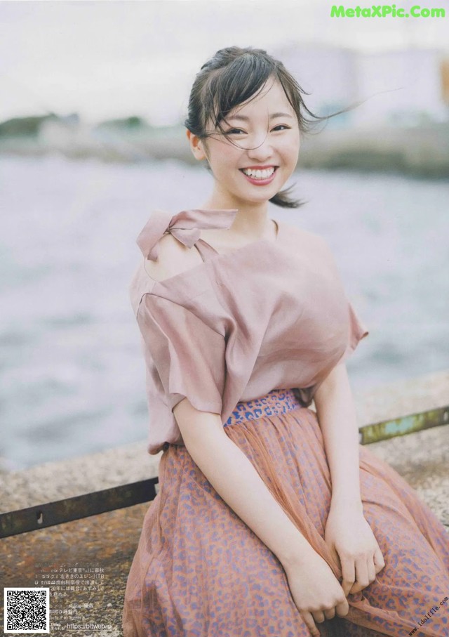 A woman sitting on a bench by the water.