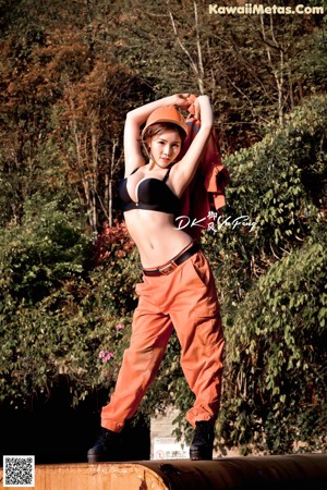 A woman in an orange jumpsuit and a hard hat posing for a picture.