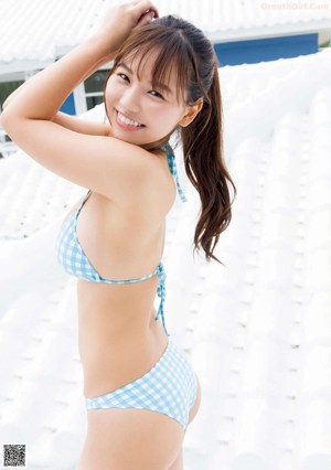 A woman in a pink bathing suit posing on a beach.