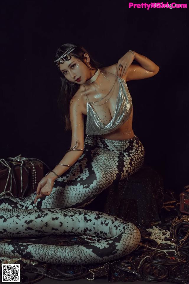A woman in a silver top and snakeskin pants posing for a picture.