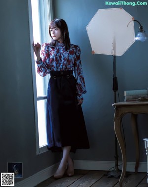 A woman in a blue skirt and a red blouse posing for a magazine.