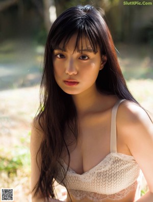 A woman in a white bra sitting on the ground.