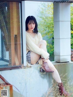 A woman in a white lingerie leaning against a window.