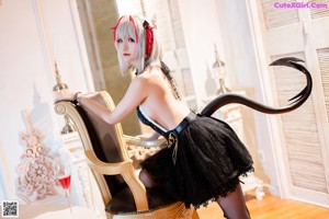 A woman in a black dress with horns on her head.
