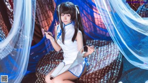 A woman in a white and blue outfit sitting on a bed.