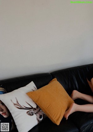 A woman sitting on top of a black couch.