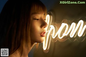 A naked asian woman leaning against a wall with a light bulb.