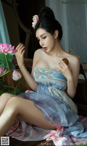 A woman sitting on a wooden bench next to a lotus flower.