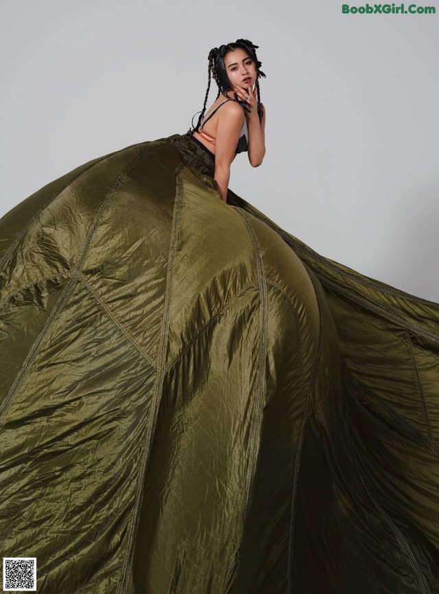 A woman standing on top of a large green tent.