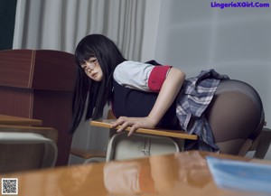 A woman laying on top of a desk in a classroom.