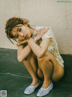 A woman leaning against a wall with a bridge in the background.