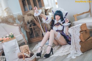 A woman in a maid outfit sitting on a chair.
